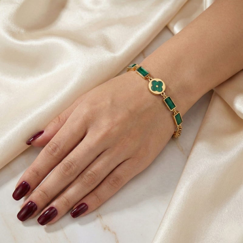 An elegant gold bracelet made of rust-resistant stainless steel, featuring a small, distinctive green flower at its center, adorned with green stones. It has an adjustable clasp for a perfect fit. - Image 2